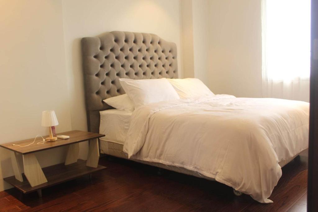 a bedroom with a white bed and a table with a lamp at Tambuli maribago residence condominium in Maribago