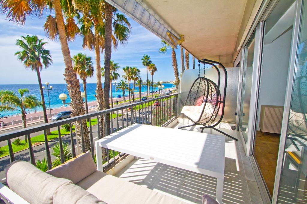 un balcón con un sofá, palmeras y el océano en Luxury sea front suite Promenade, en Niza