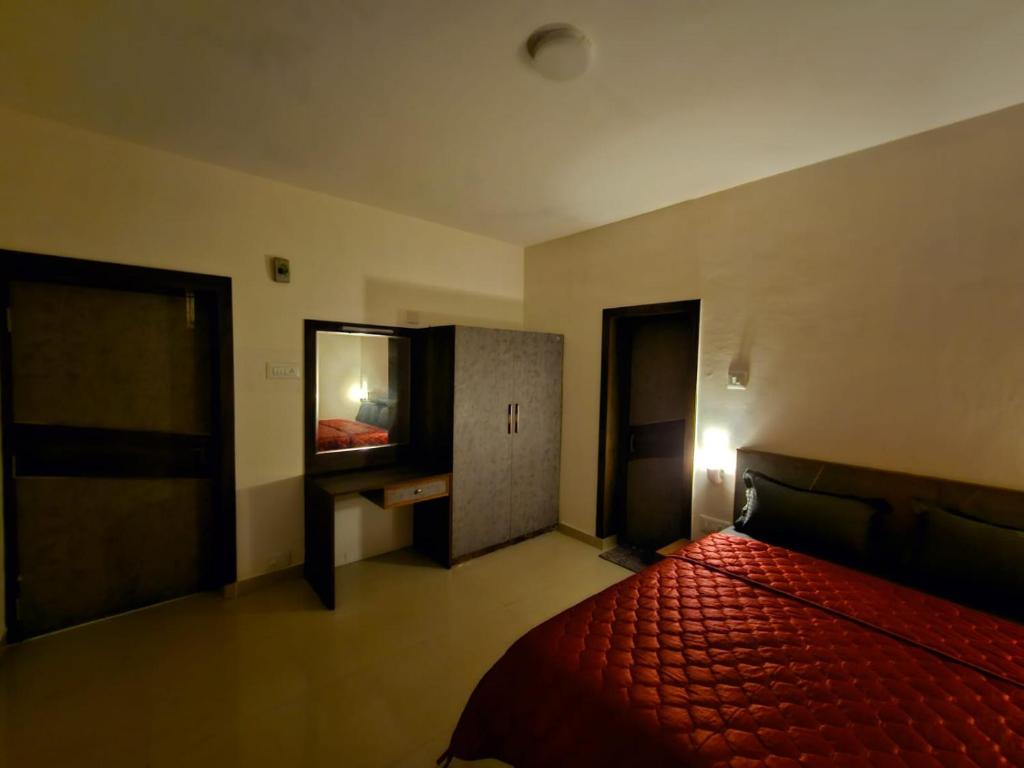 een slaapkamer met een rood bed en een televisie bij July17 residency in Kodaikānāl