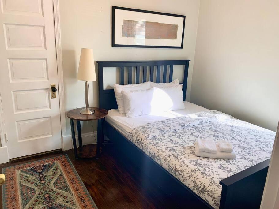 een slaapkamer met een bed en een tafel met een lamp bij The House Hotels - Ridgewood Lower in Lakewood