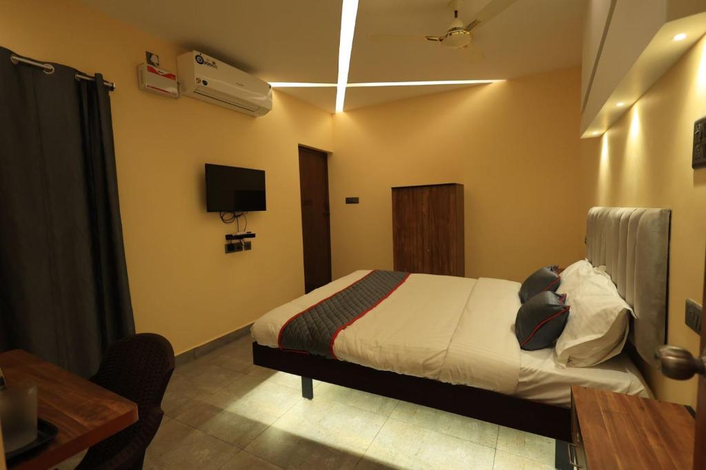 a bedroom with a bed and a table and a tv at AMR Inn in Pondicherry