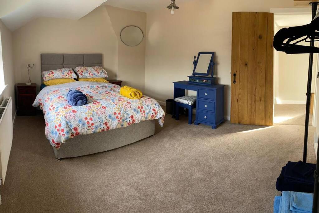 a bedroom with a bed and a dresser and a mirror at Newton Hall farm cottage with amazing views & hot tub in Preston