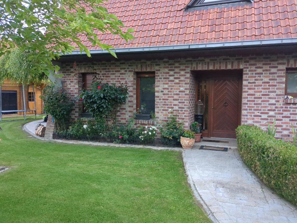 een stenen huis met een bruine deur en een tuin bij Villa Elena in Camphin-en-Pévèle