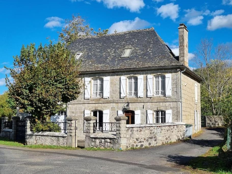 une ancienne maison en pierre sur le côté d'une route dans l'établissement Maison La Rase du Lac Cantal, à Menet
