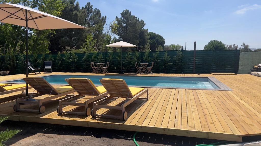 a deck with two chairs and a swimming pool at Chalé do Vale in Pinhal Novo