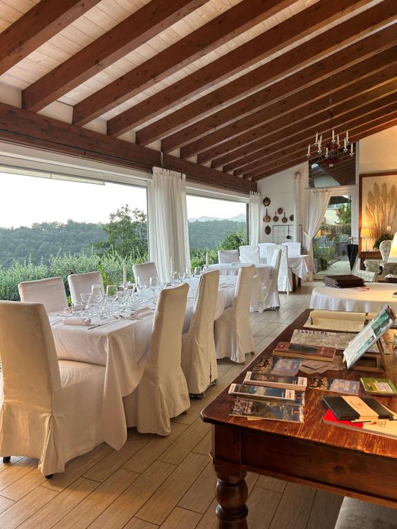 una sala da pranzo con tavoli bianchi e sedie bianche di Agriturismo Al Robale ad Almenno San Bartolomeo