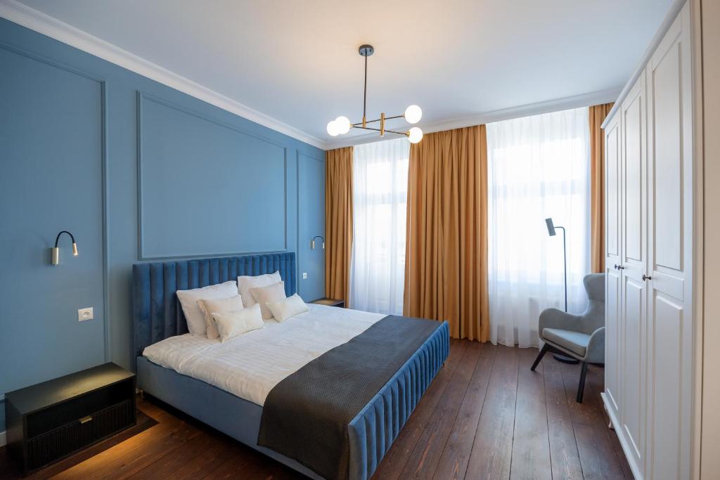 a blue bedroom with a bed and a chair at Tajemniczy Ogród (w sercu toruńskiej Starówki) in Toruń