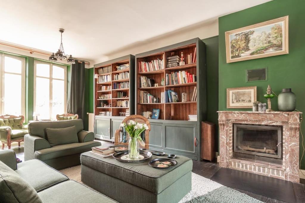 a living room with a fireplace and green walls at Maison Corbionne - Au cœur du Perche in Condeau