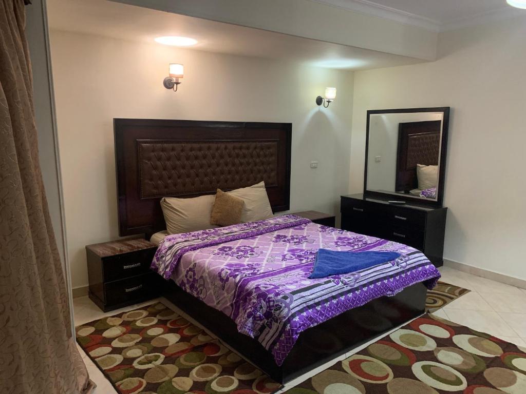 a bedroom with a bed with a purple comforter and a mirror at Airport hostel room for transit in Cairo