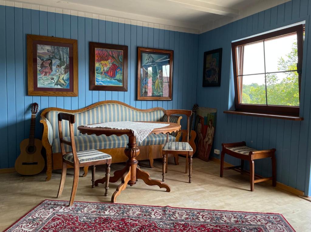 Cette chambre est dotée de murs bleus, d'une table et de chaises. dans l'établissement Dom Pod Dobrym Drzewem, à Inowłódz