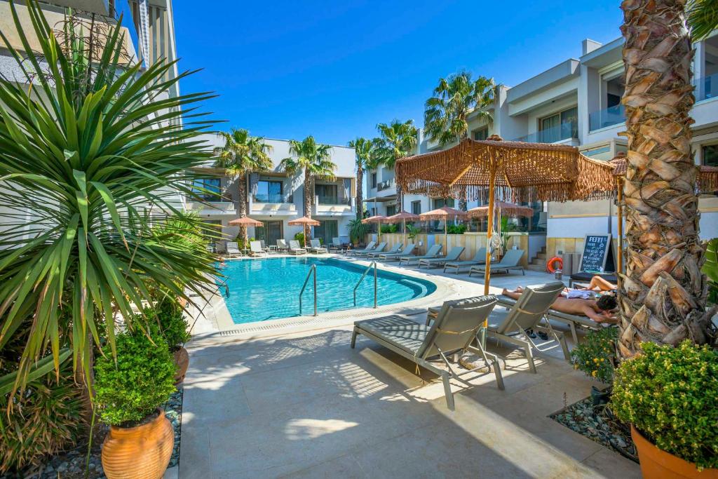 a pool with chairs and umbrellas next to a building at Pefki Deluxe Residences in Pefkohori