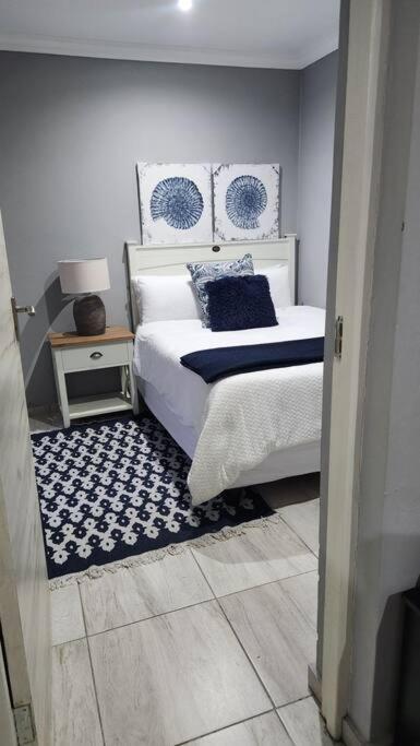 a bedroom with a bed with blue and white pillows at Tranquility on St James in Johannesburg