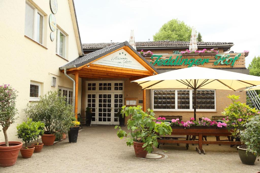 a restaurant with a bench and an umbrella and plants at Jeddinger Hof Land- und Seminarhotel in Visselhövede
