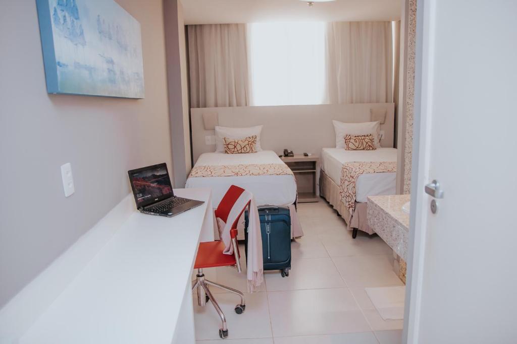 a hotel room with two beds and a suitcase at Rede Andrade Lapa in Rio de Janeiro