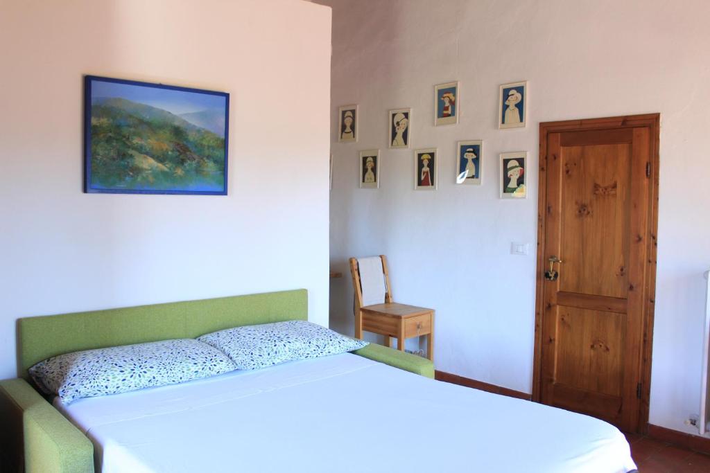una camera con un letto bianco e una porta in legno di AU-RA Vegan B&B a Castagneto Carducci
