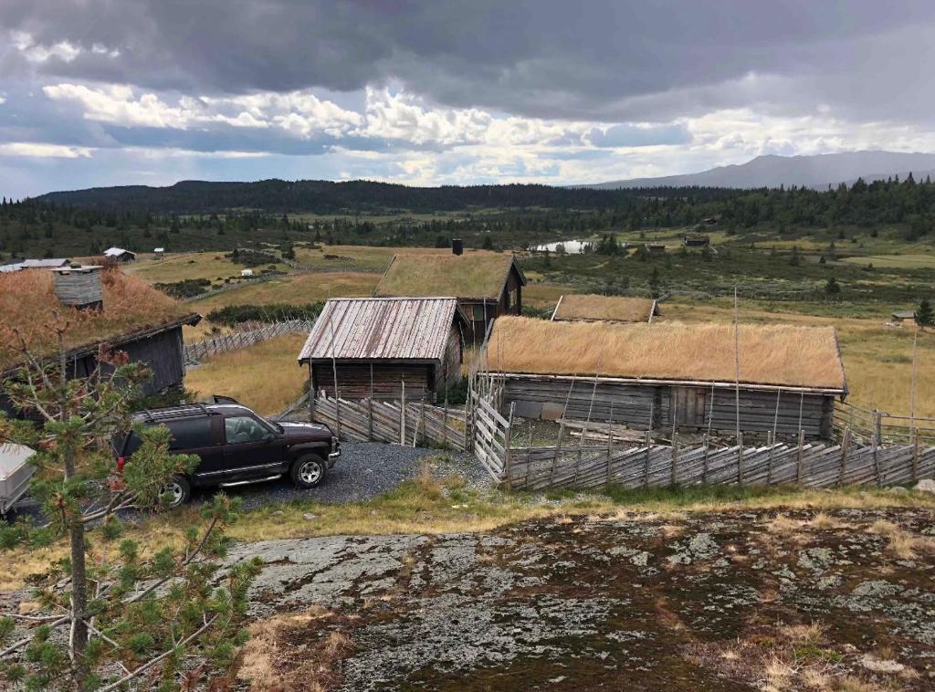 a car parked in front of two barns in a field at Hytte på idyllisk seter in Fosset