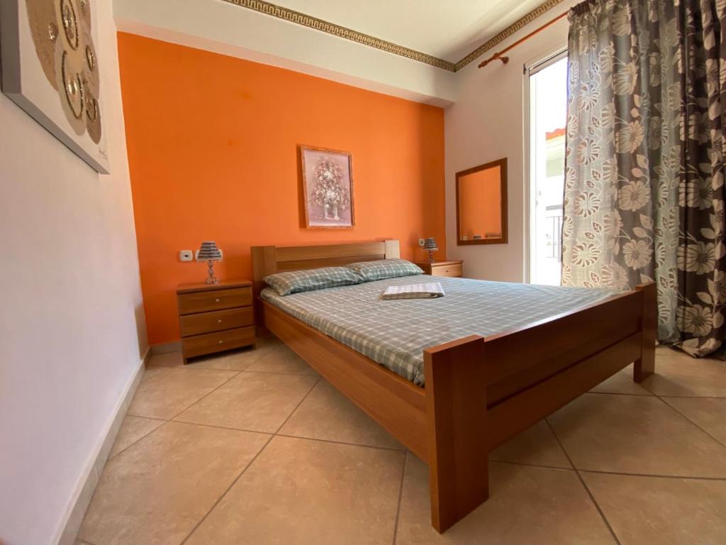 a bedroom with a bed with an orange wall at Roula apartment in Nei Poroi