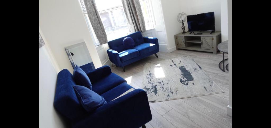 a living room with two blue chairs and a television at West Lake District Comfort Stays in Maryport town centre in Maryport