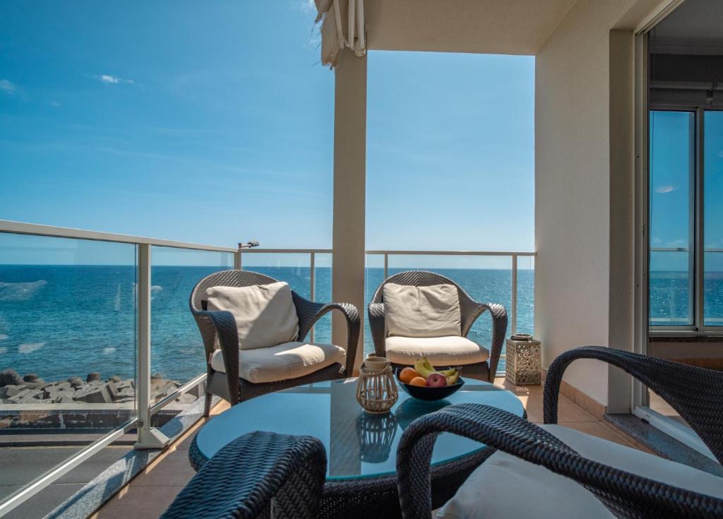einen Balkon mit einem Tisch, Stühlen und Meerblick in der Unterkunft Front beach Apartment in Paul do mar 9 in Paul do Mar