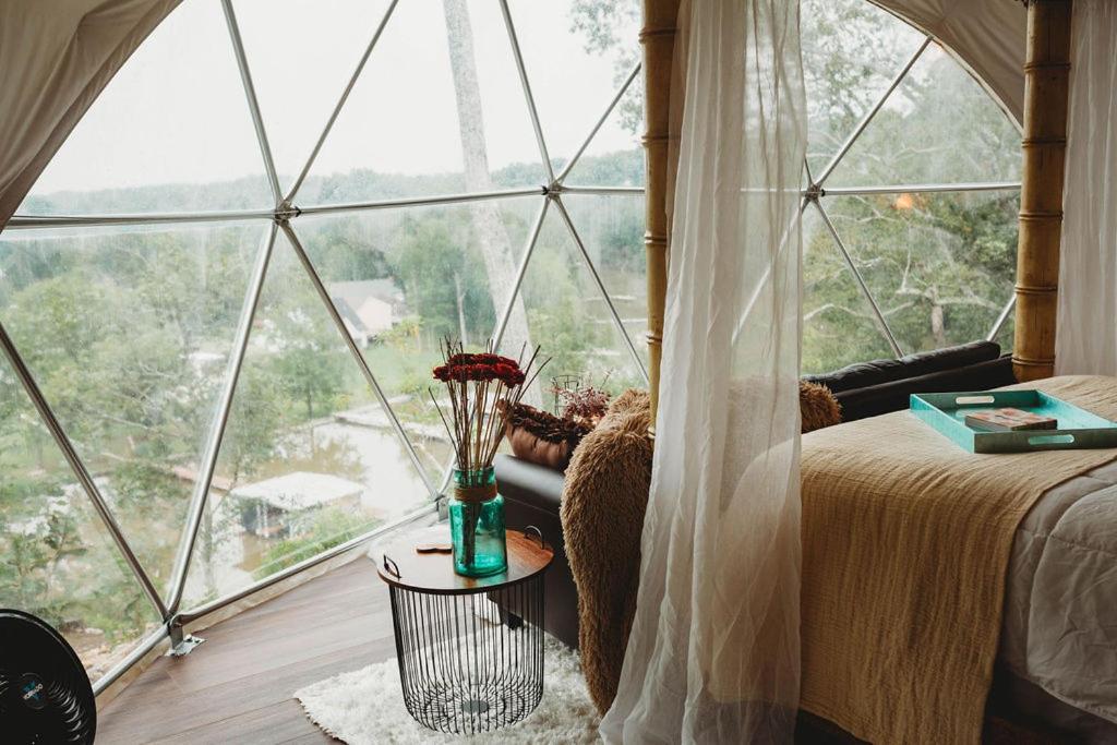 a bedroom with a bed and a large window at WATERFRONT LUXURY GLAMPING DOME in Rogersville