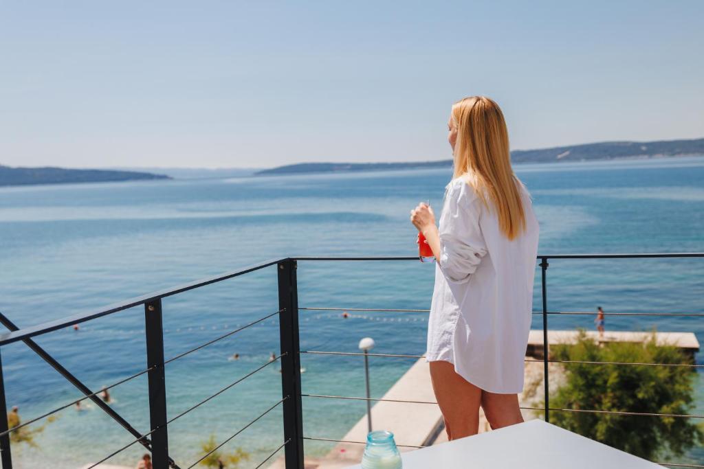 a woman standing on a balcony looking at the water at Hotel Štacija in Kaštela