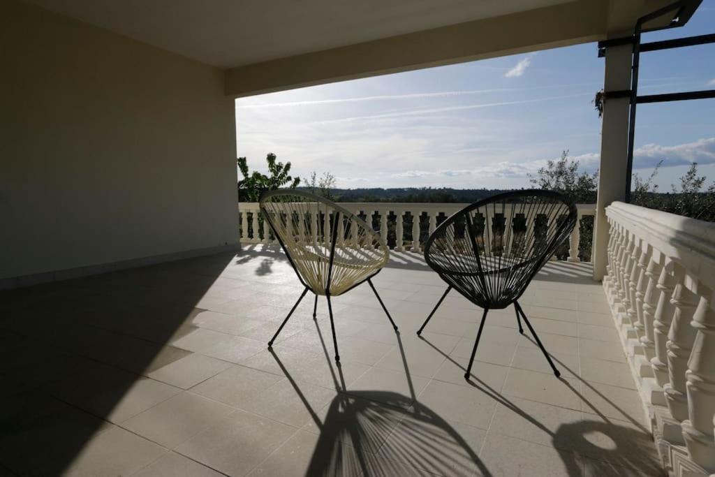 Duas cadeiras sentadas num alpendre com vista para o oceano em Villa Mendes Oliva em Almeida