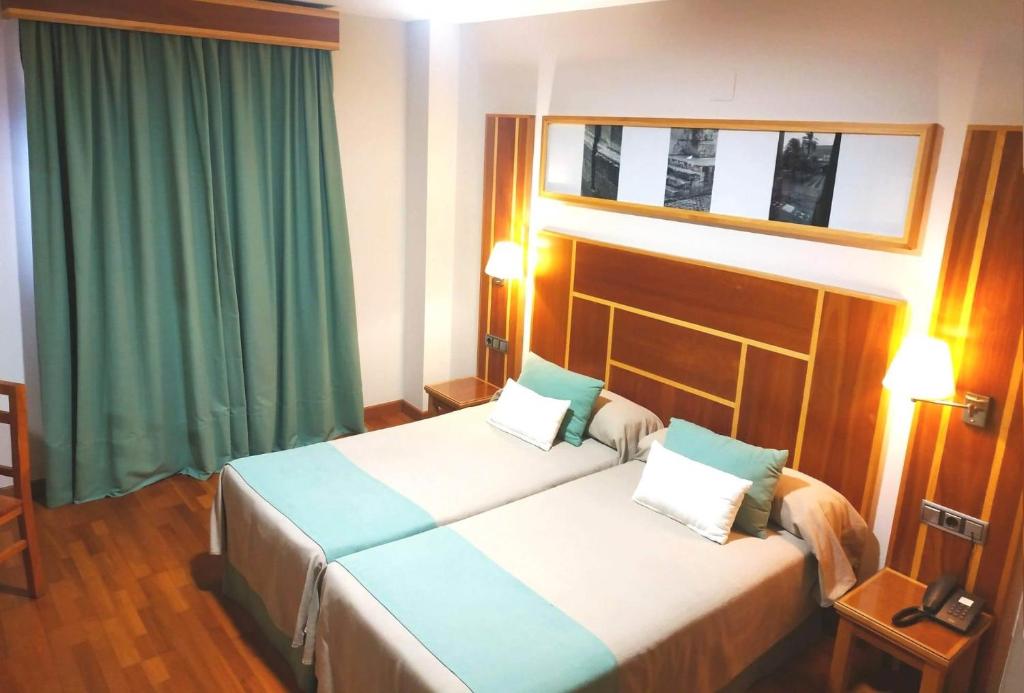 ラ・カルロータにあるHotel Carmenのベッド2台と緑のカーテンが備わるホテルルームです。