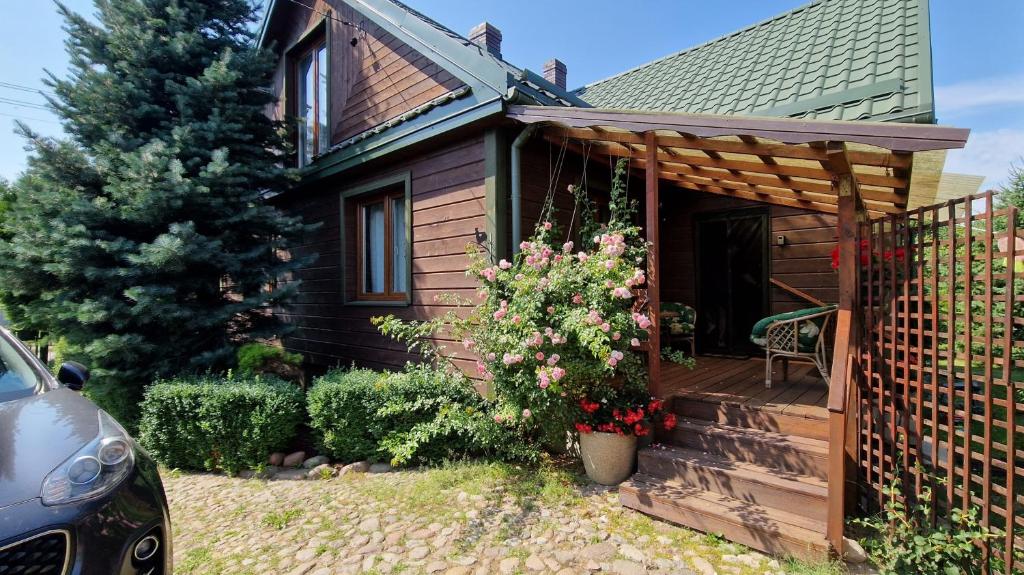 een hut met een veranda met een stoel en bloemen bij Dierewnia-chata blisko Białowieży 
