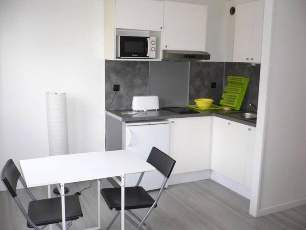a white kitchen with a table and a microwave at Appartement Nickel et confortable in Rouen