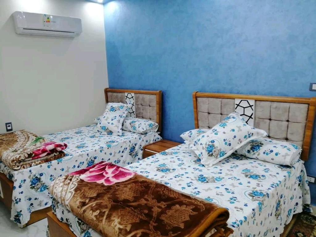 2 łóżka w pokoju z niebieskimi ścianami w obiekcie برج الهنا w Aleksandrii