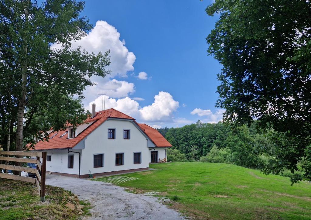 ein weißes Haus mit rotem Dach auf einem Feld in der Unterkunft Ubytování U Bohouše in Horní Radouň