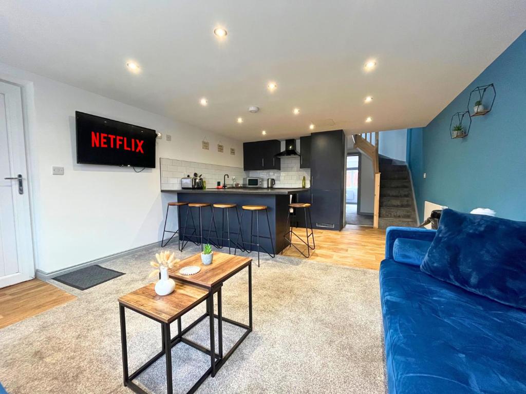 a living room with a blue couch and a kitchen at Modern 3 Bedroom House, Sleeps 6 - Free Parking & Garden - Opposite Racecourse, Near City Centre & Hospital in Doncaster