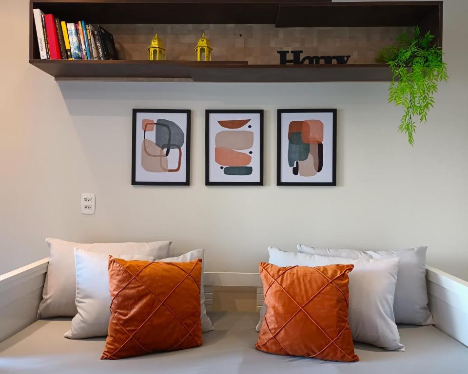 un sofá con 3 almohadas y 3 cuadros en la pared en Apartamentos Juliana Bela Vista, en São Paulo