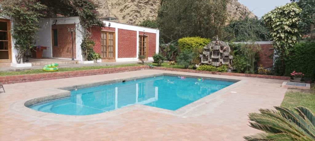 a swimming pool in front of a house at Las buganvilias in Pachacamac