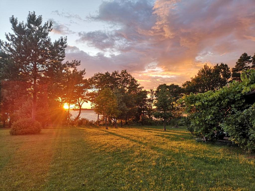 a sunset in a field with trees and a lake at Lake View Home in Rajgród