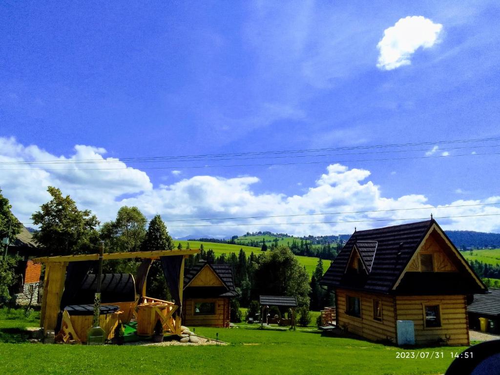 una cabaña de madera en un campo de césped verde en Domek u Śpiewoka 1, en Maruszyna