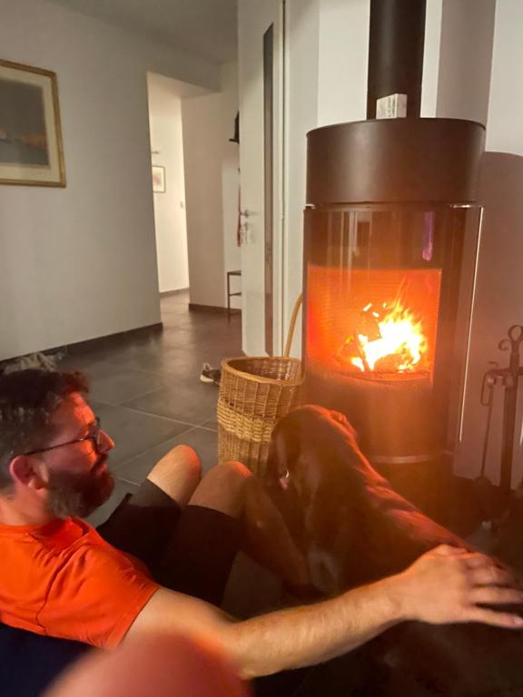 un hombre sentado en un sofá frente a una chimenea en Chez Olivier et Damien en La Roche-sur-Yon