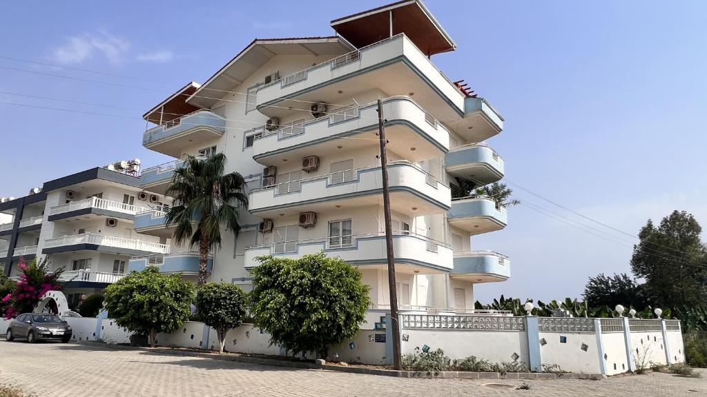 a tall white building with a car parked in front of it at Marina Residence Suit 5 in Gazipasa