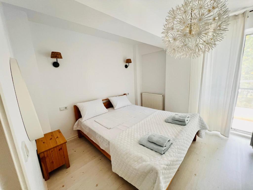 a white bedroom with a bed and a chandelier at The Airport Loft in Otopeni