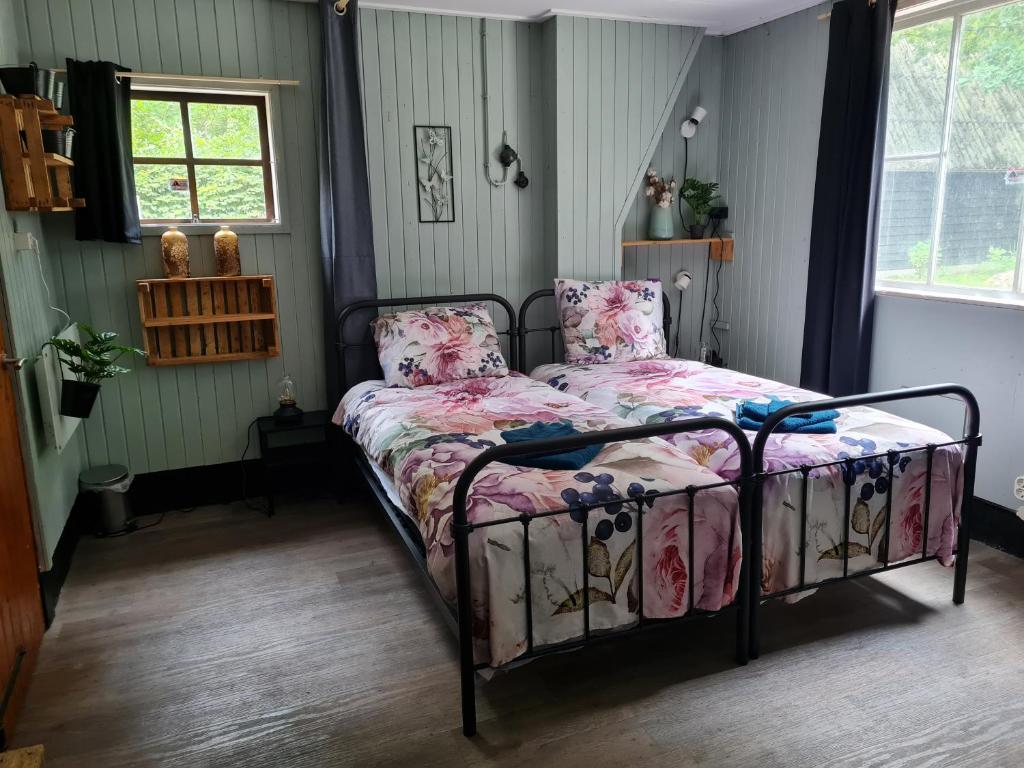 a bedroom with a bed with a floral bedspread at de Tweelingen in Schoonloo
