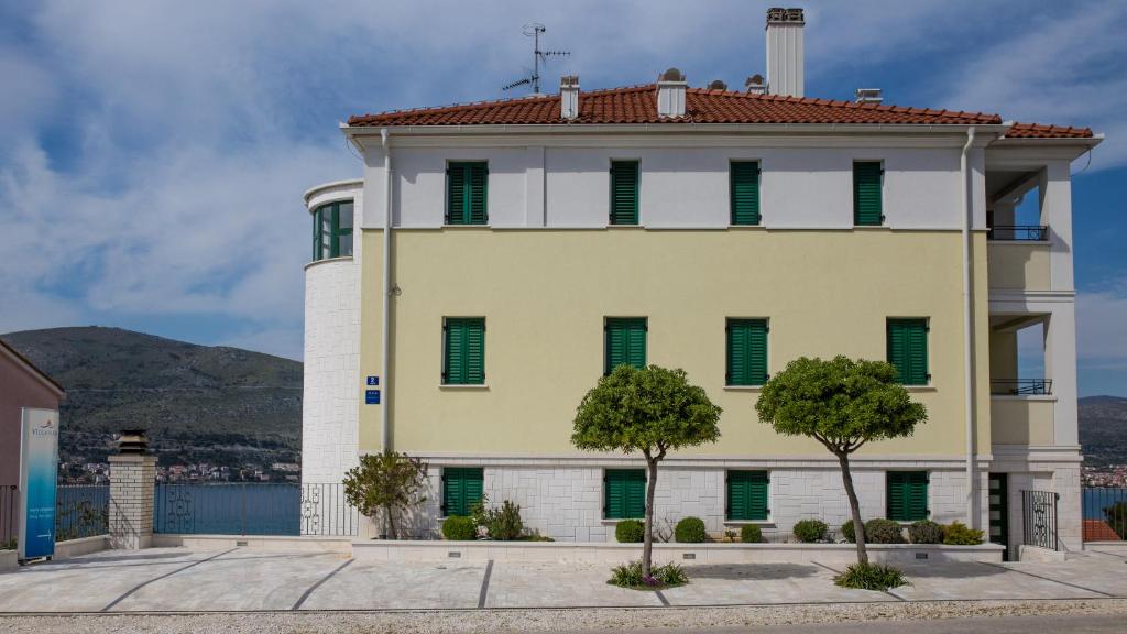 a large yellow building with green shuttered windows at Apartments Villa Novak 1 in Okrug Donji