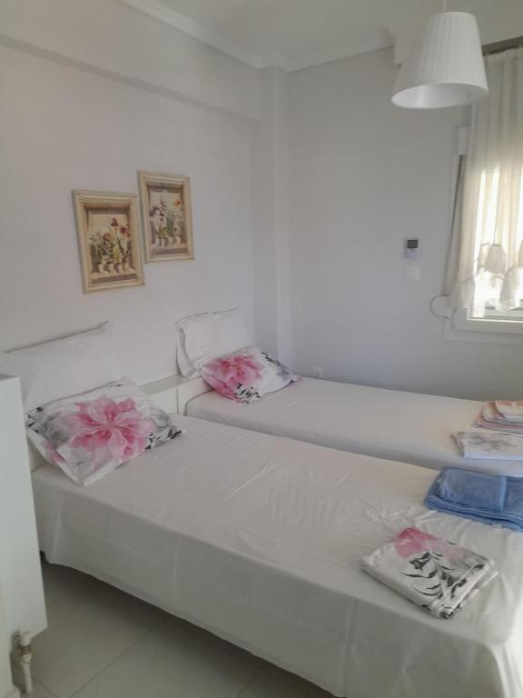 two beds in a white room with pink pillows at Annas seaside apartment in Perea