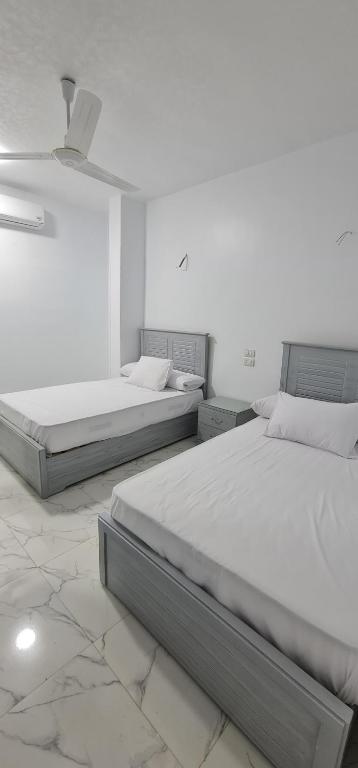 1 dormitorio con 2 camas y ventilador de techo en Nuba Heart, en Asuán