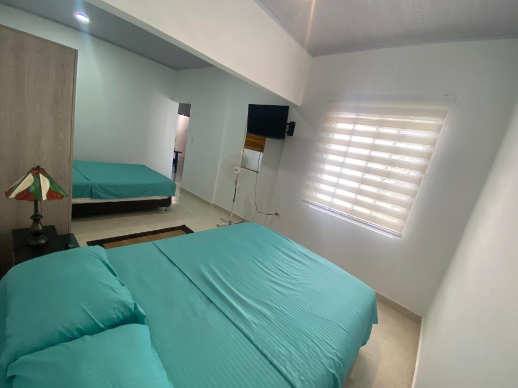 Un dormitorio con una cama azul y una ventana en IW-Apto en la vega, cerca al CC Viva, en Villavicencio
