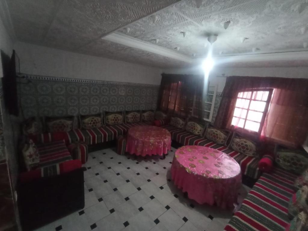 a room with couches and tables and a window at Sablettes in Oulad Akkou