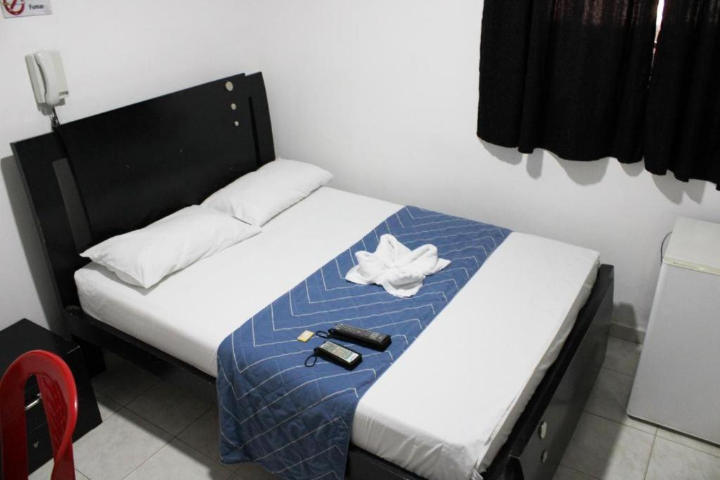 een kleine slaapkamer met een bed met een blauwe deken bij Hotel Villa Rocio Curumani in Curumaní