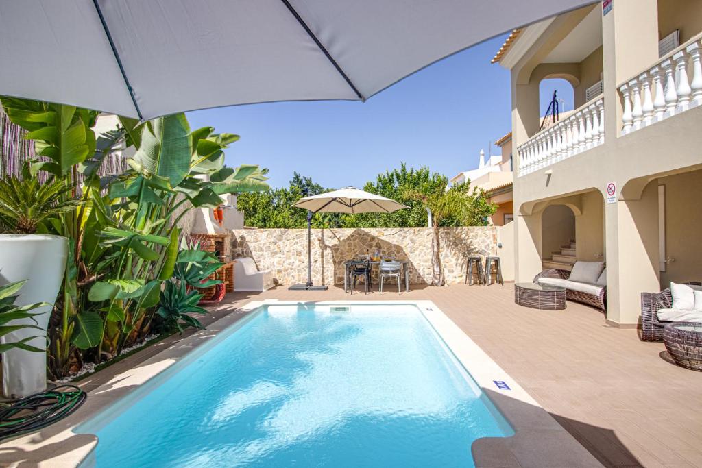 a swimming pool in a house with an umbrella at Private Deluxe 3BD Villa Pool Wi-Fi AC BBQ in Albufeira