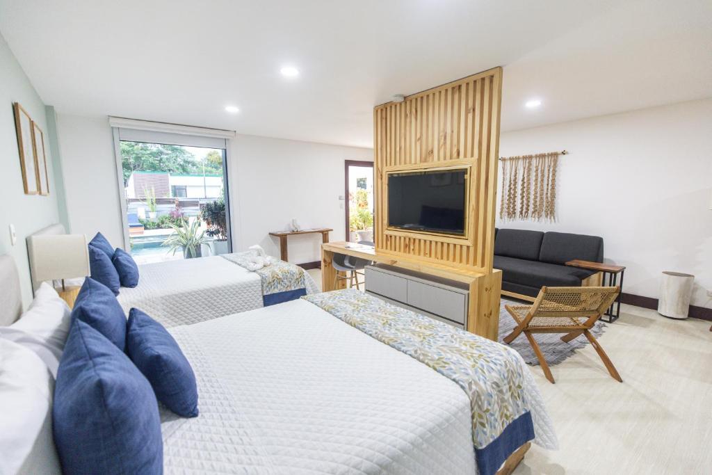 a hotel room with two beds and a television at Paradise Bay Hotel Boutique in Herradura