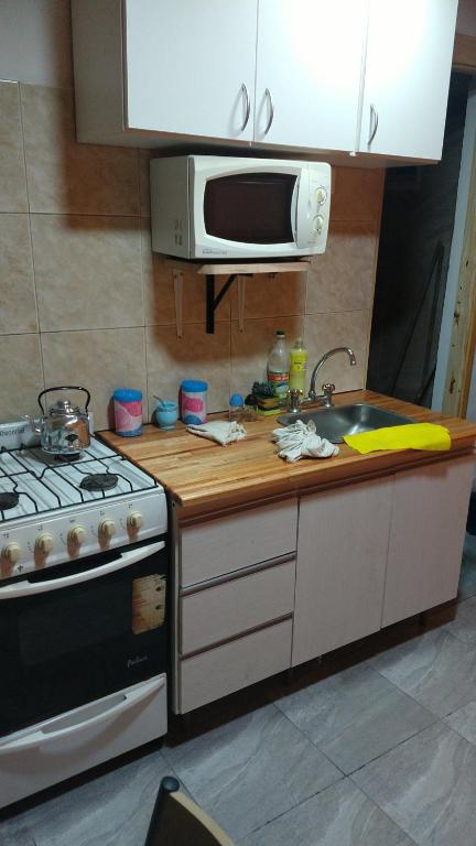 a kitchen with a stove and a sink and a microwave at Depto Pablo in Olavarría