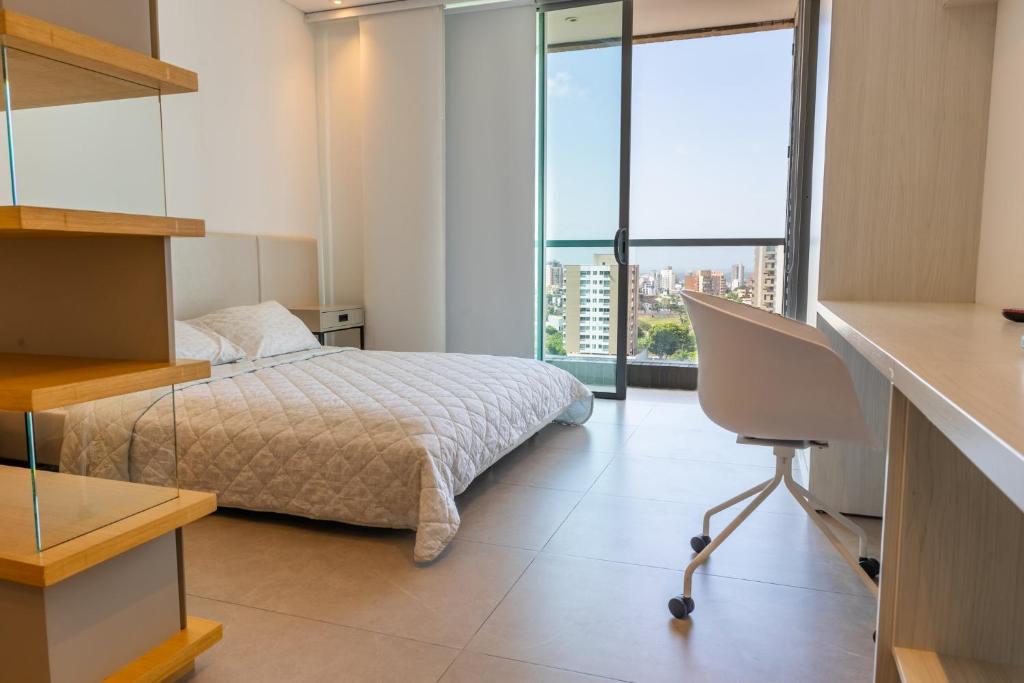 een slaapkamer met een bed en een bureau met een stoel bij Distrito 90 in Barranquilla